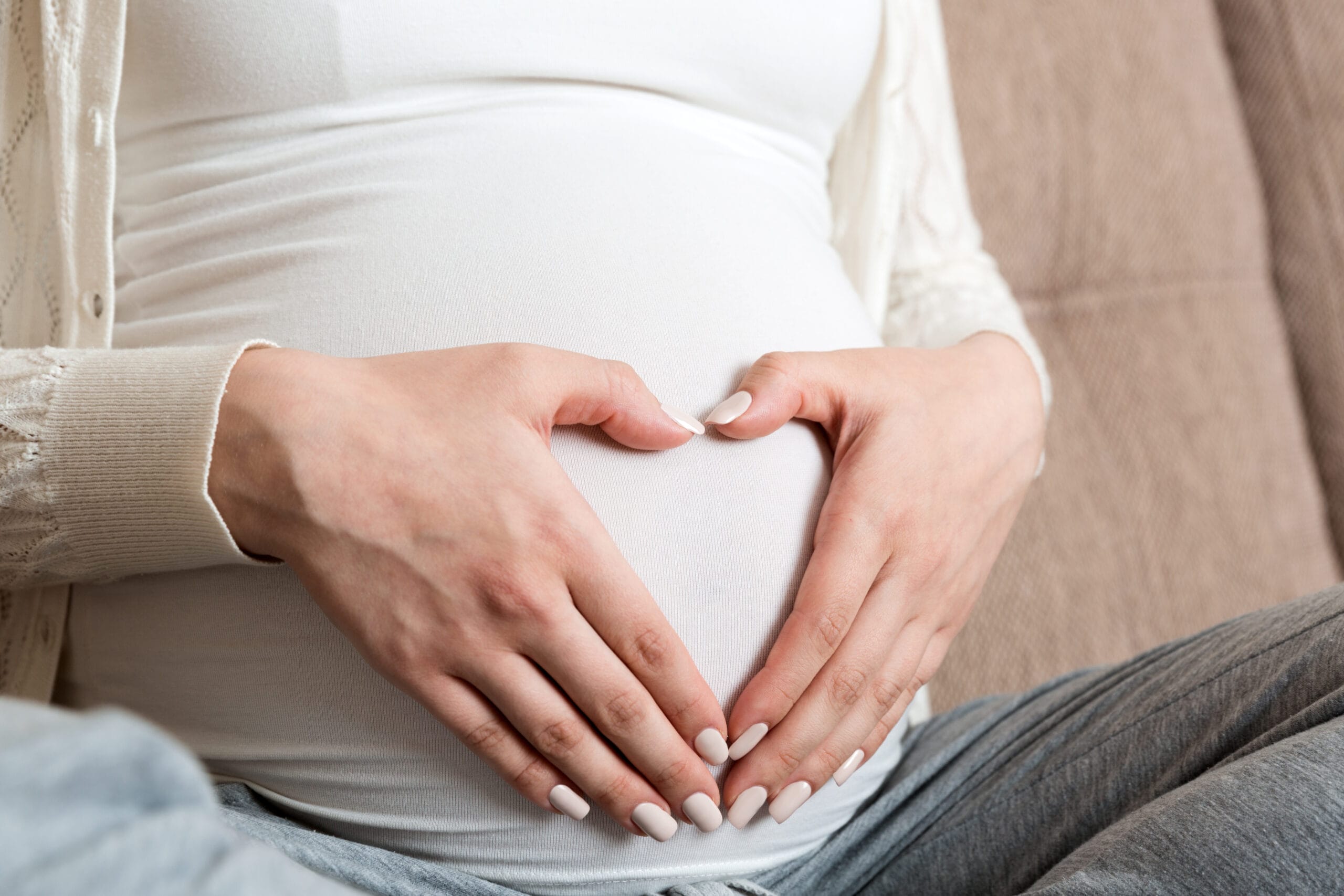 Young pregnant woman holds wooden heart. Love concept