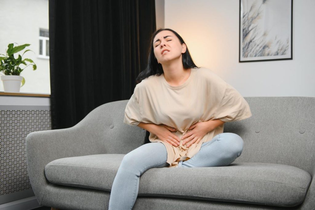 woman sitting on couch in pain
