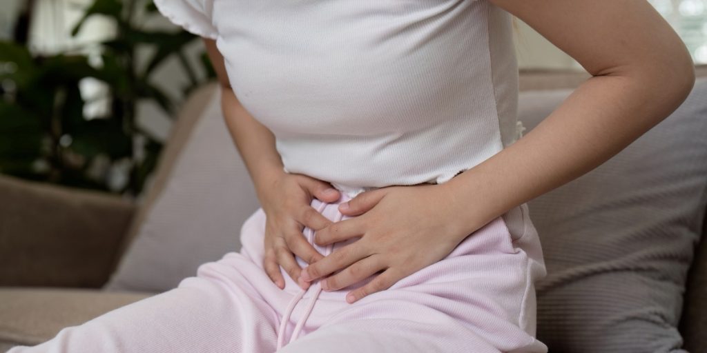 Woman Experiencing Stomach Pain While Sitting on a Couch