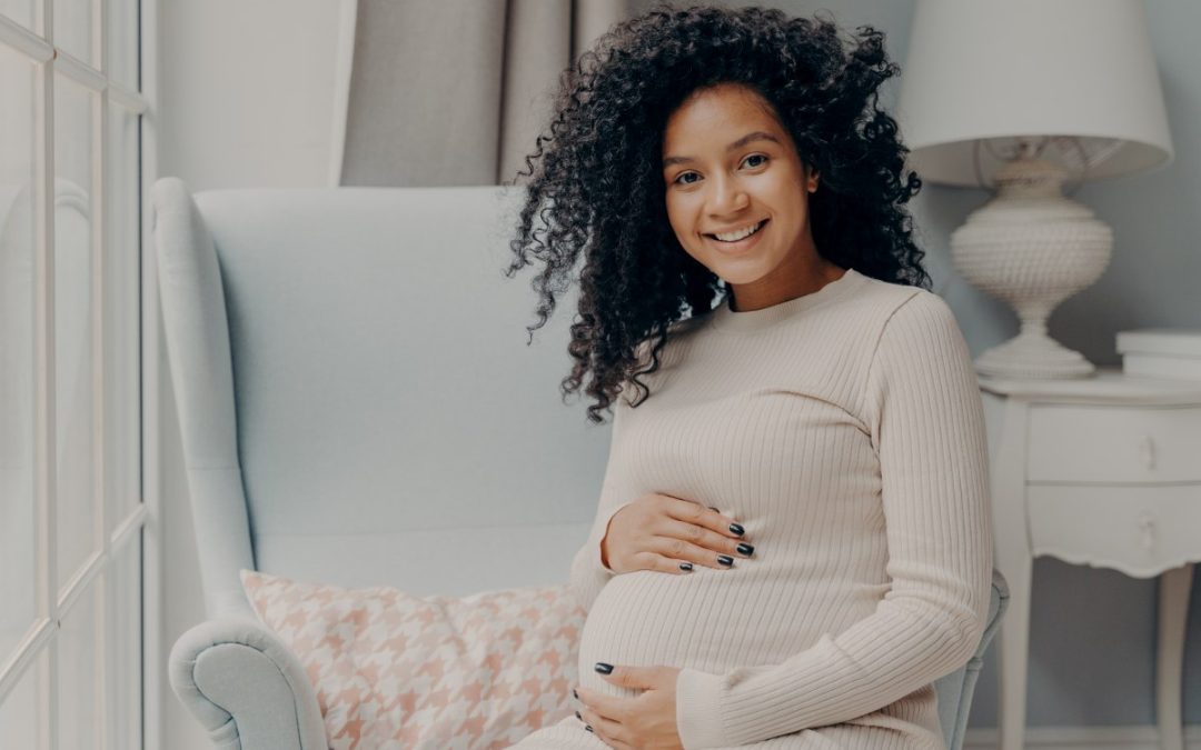 beautiful pregnant woman smiling while holding her pregnant belly