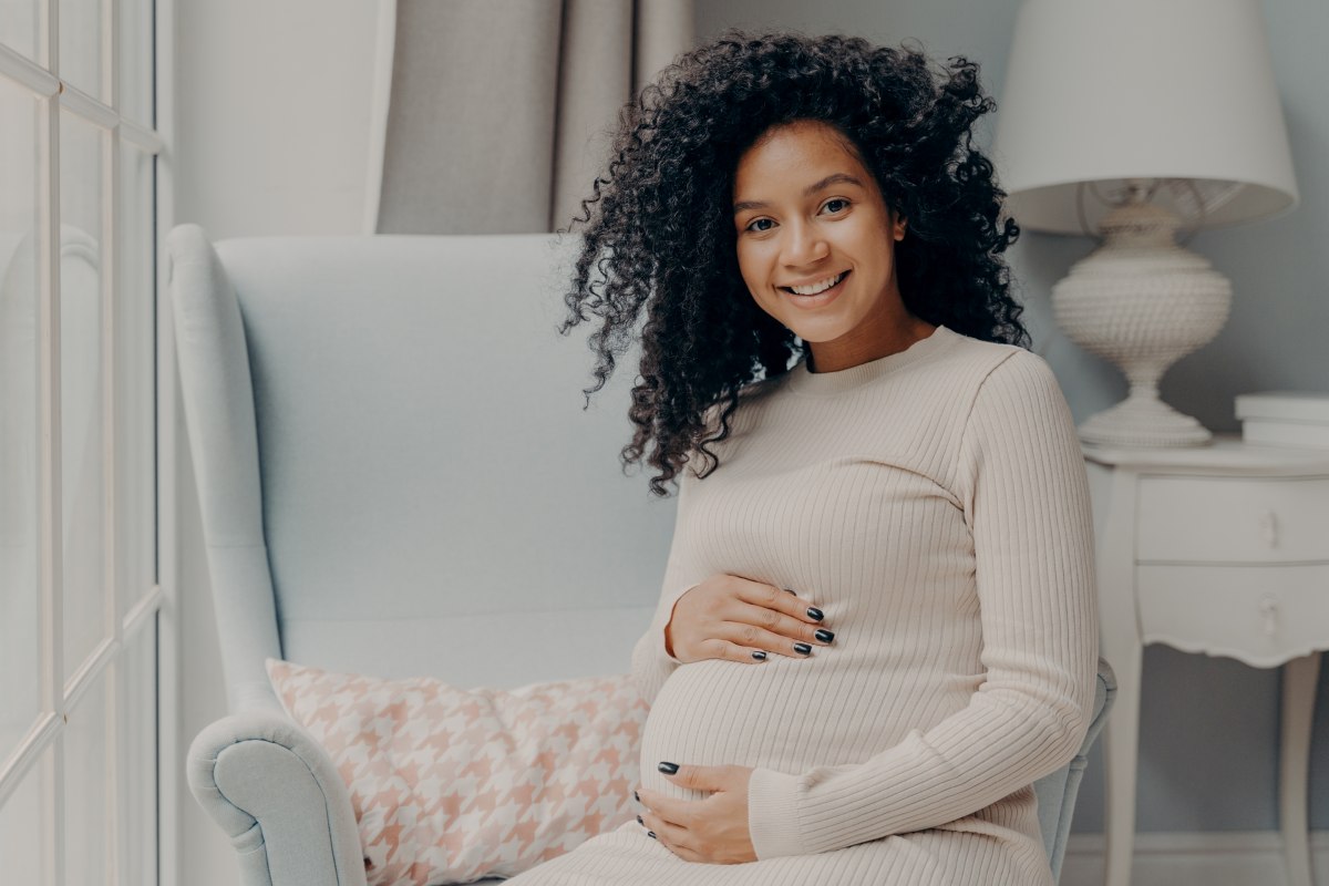 beautiful pregnant woman smiling while holding her pregnant belly