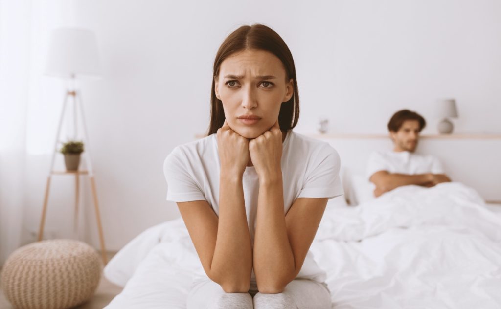 woman sitting on bed with a sad look on her face