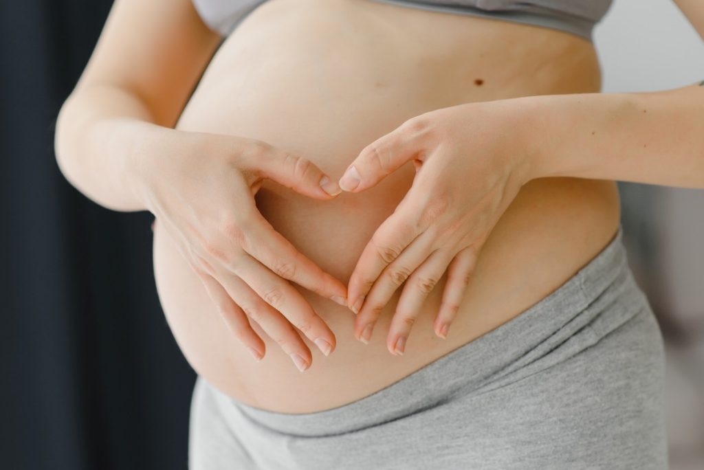 pregnant woman holds her hands on her swollen belly