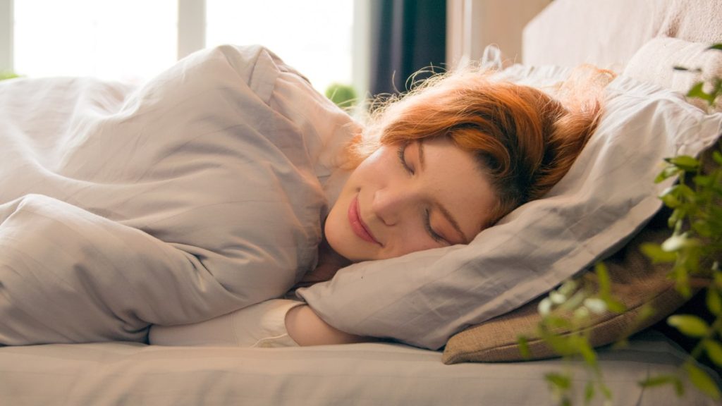 happy woman sleeping in comfortable cozy bed at home