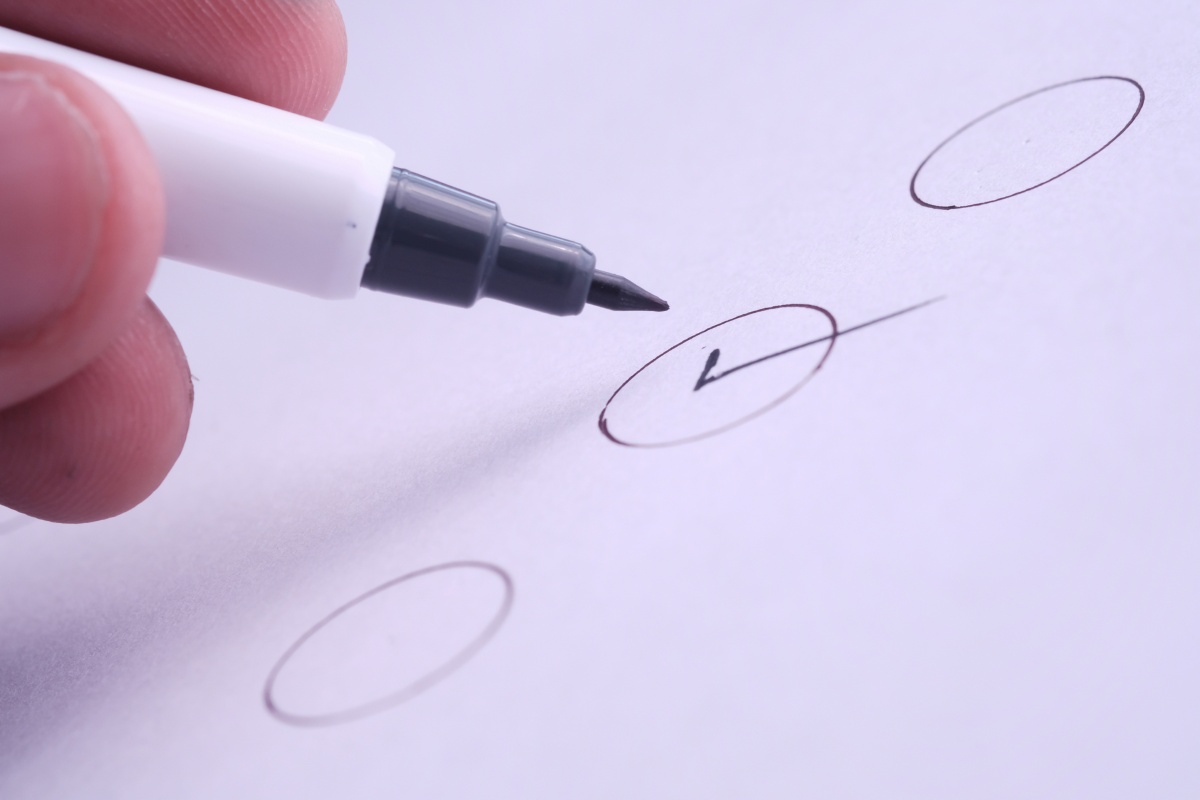 first trimester pregnancy checklist hand grasping a pen, diligently marking a checklist on a piece of paper