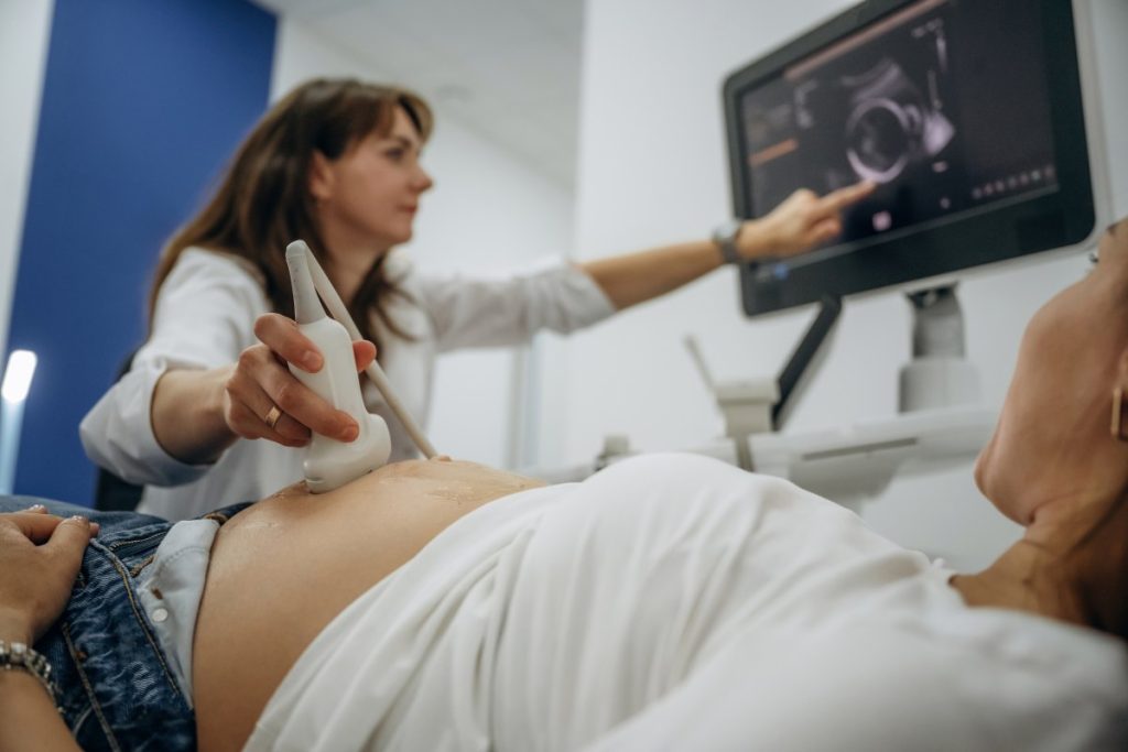 A woman is holding an ultrasound machine while another woman is looking at it