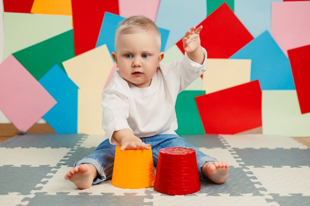 A playful baby happily engaged with a set of colorful stacking cups