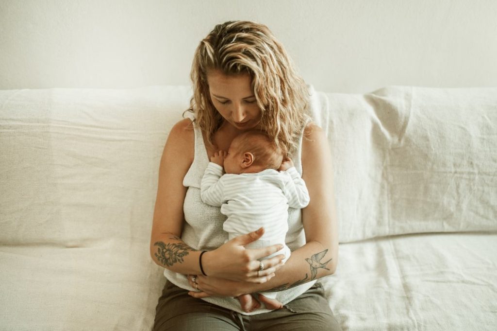 Maternity, mama relax and newborn child in a family house with mom and young kid together with youth on a lounge couch