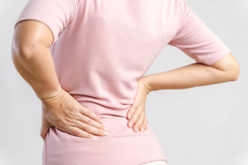 Young woman feeling pain in her back on white background